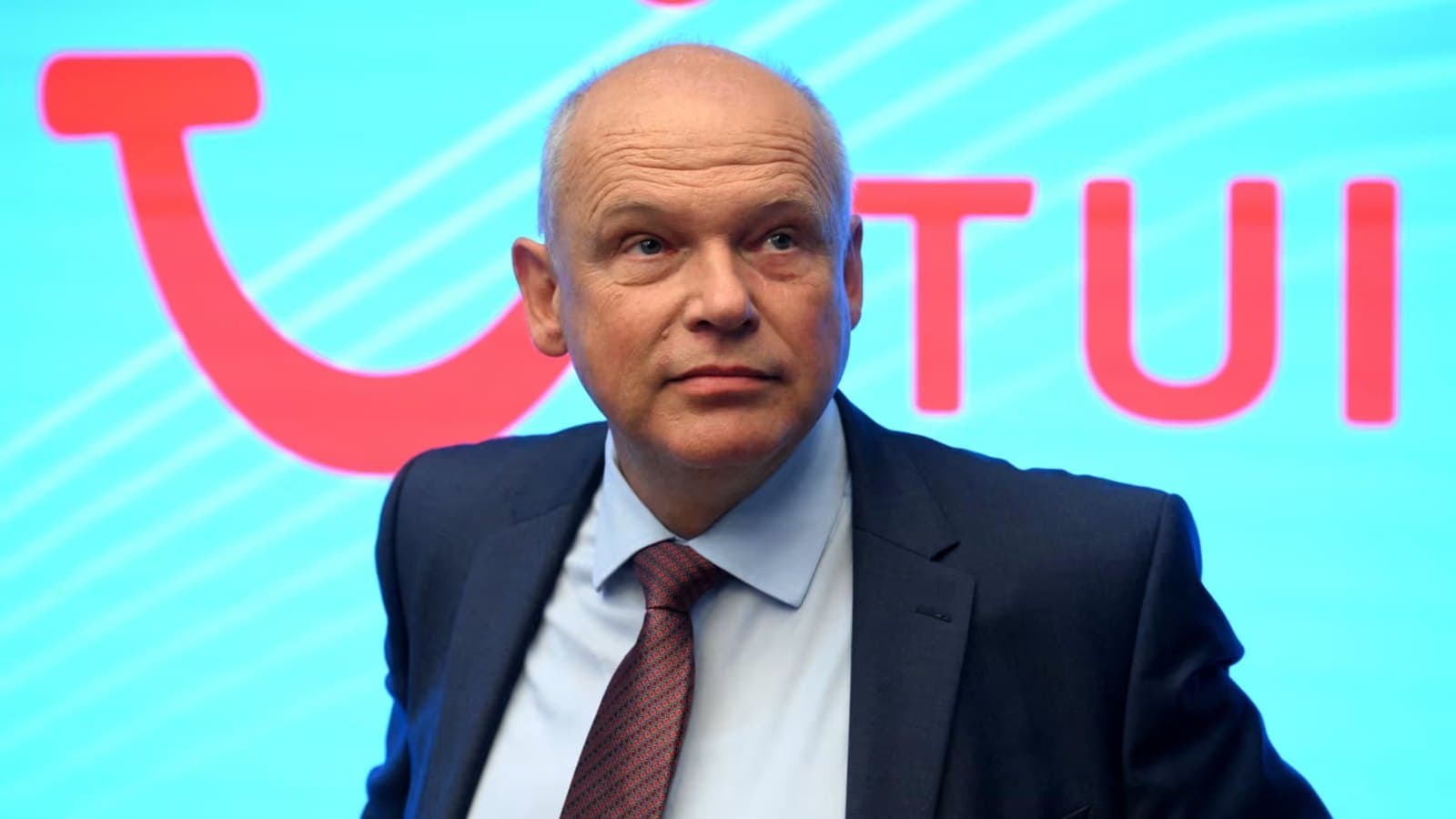 El consejero delegado de TUI, Sebastian Ebel, fotografiado ante un gran logotipo iluminado de TUI.