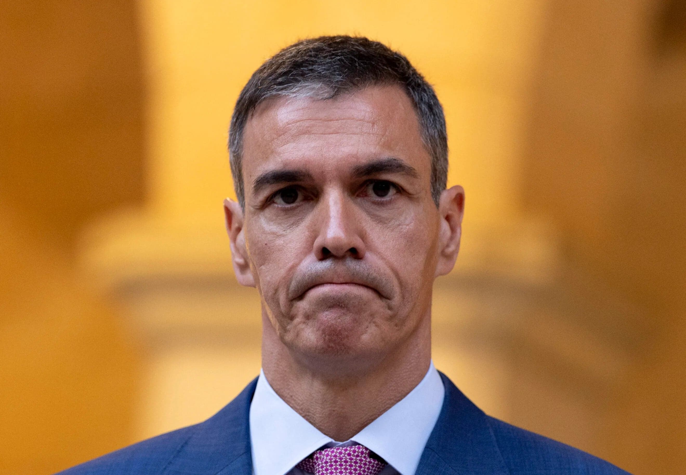El presidente del Gobierno, Pedro Sanchez, con gesto serio ante un fondo dorado