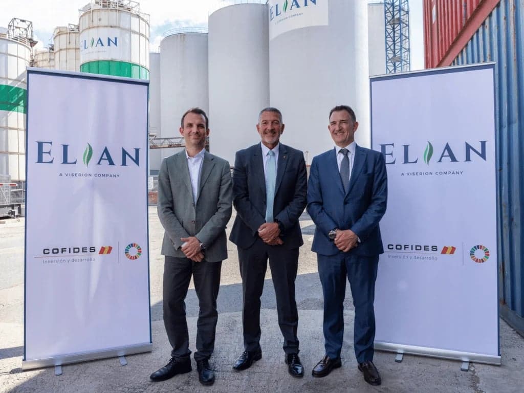 Tres directivos posan frente a los silos de la planta de Elian en el puerto de Barcelona junto a carteles de Elian y Cofides