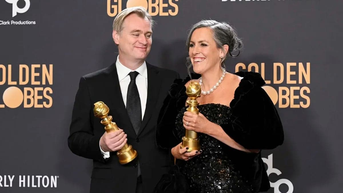 Christopher Nolan and Emma Thomas pose smiling with their awards in front of a Golden Globes backdrop