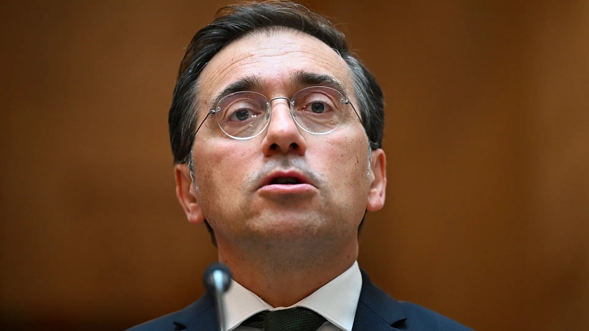 Close-up of a Spanish official wearing glasses speaking into a microphone at a public appearance