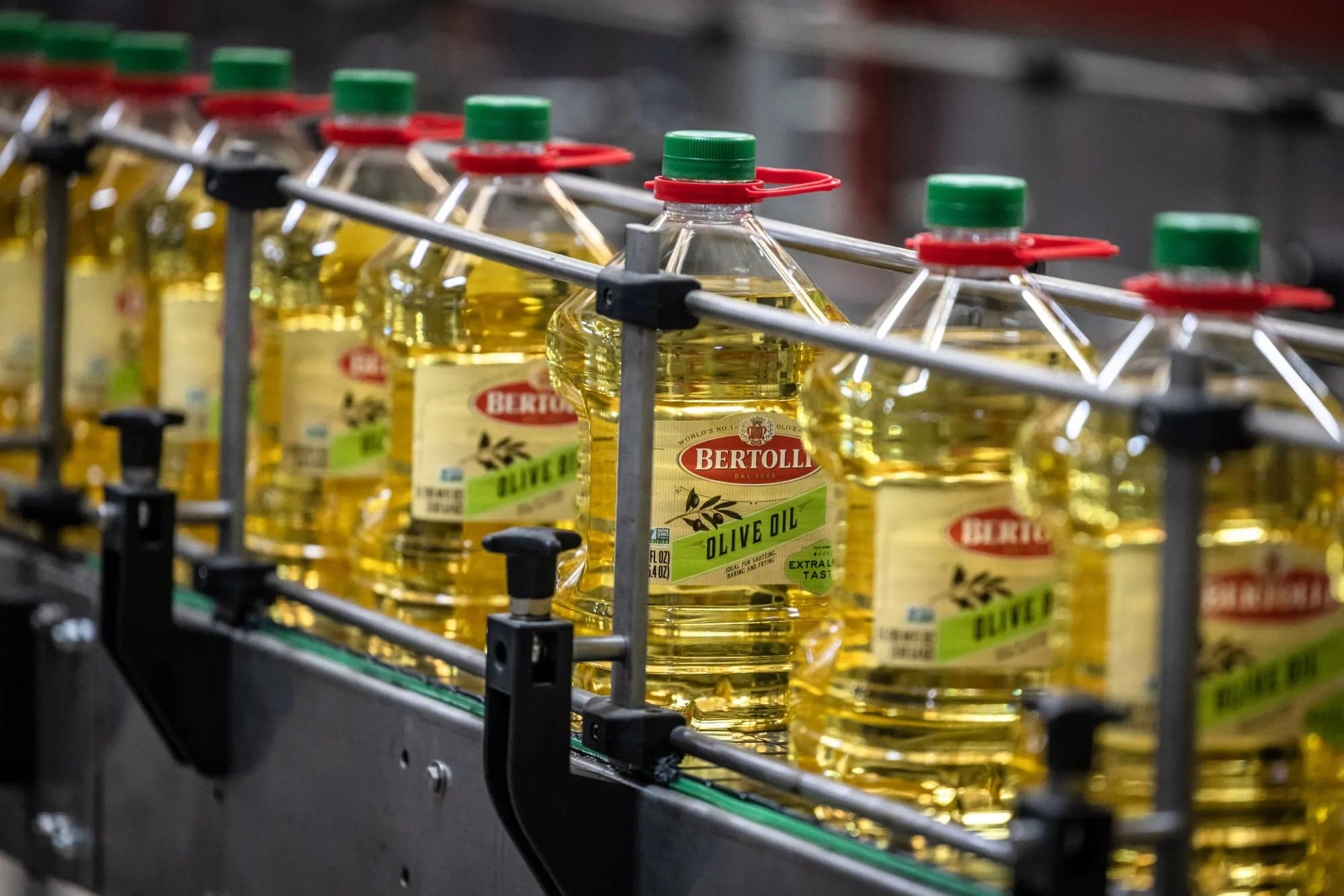Botellas de aceite de oliva de la marca Bertolli avanzan por una linea de embotellado industrial