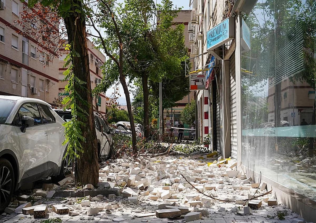 Debris from a collapsed shopfront ceiling scattered across a Granada sidewalk after an earthquake