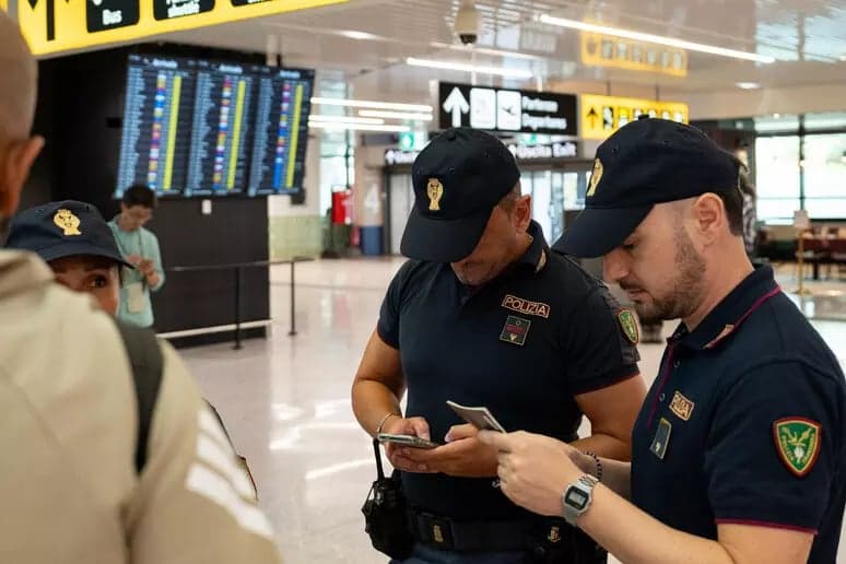 Italian police officers check travelers' documents at an airport