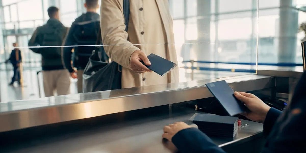 A traveler hands over a passport at an airport border control