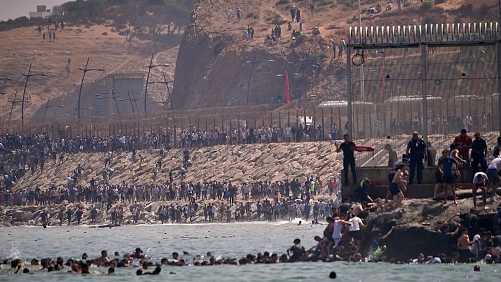 Migrants crossing the fenced border and swimming near Ceuta, Spain