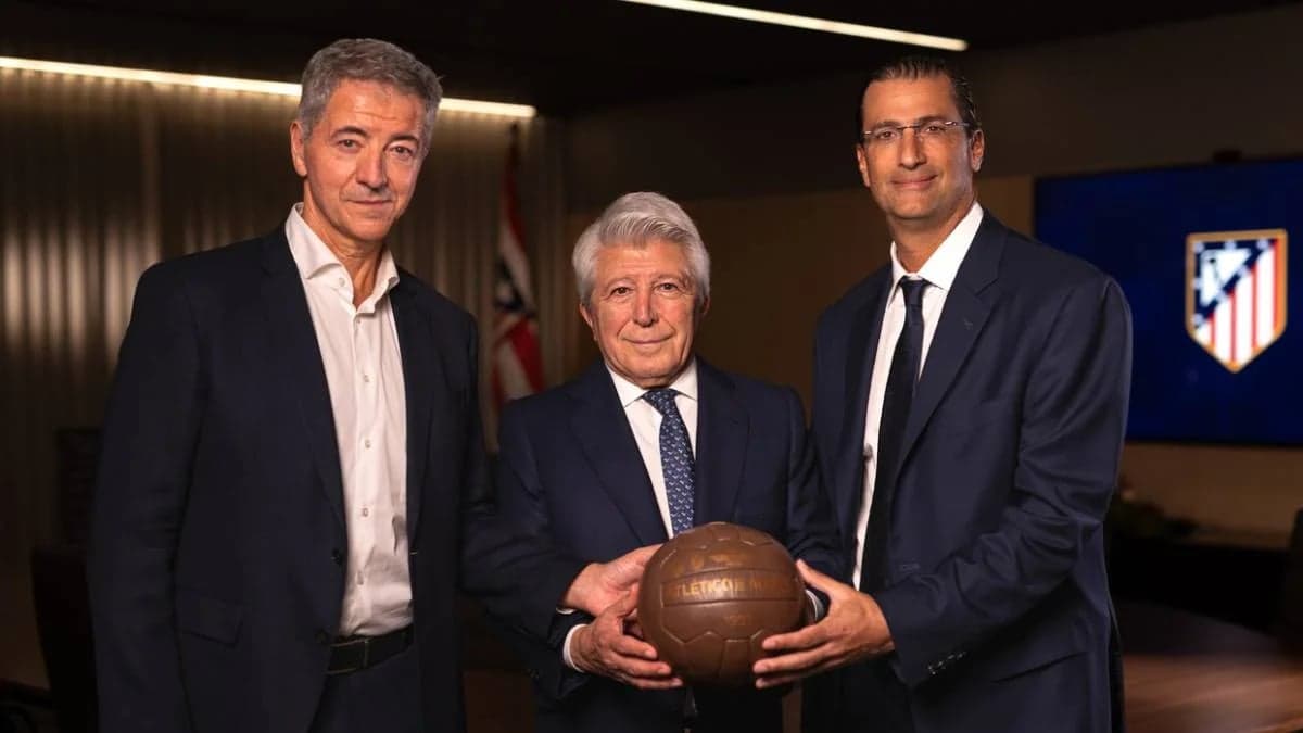 Tres directivos del Atletico de Madrid posan en una sala de juntas sosteniendo un balon antiguo con el escudo del club